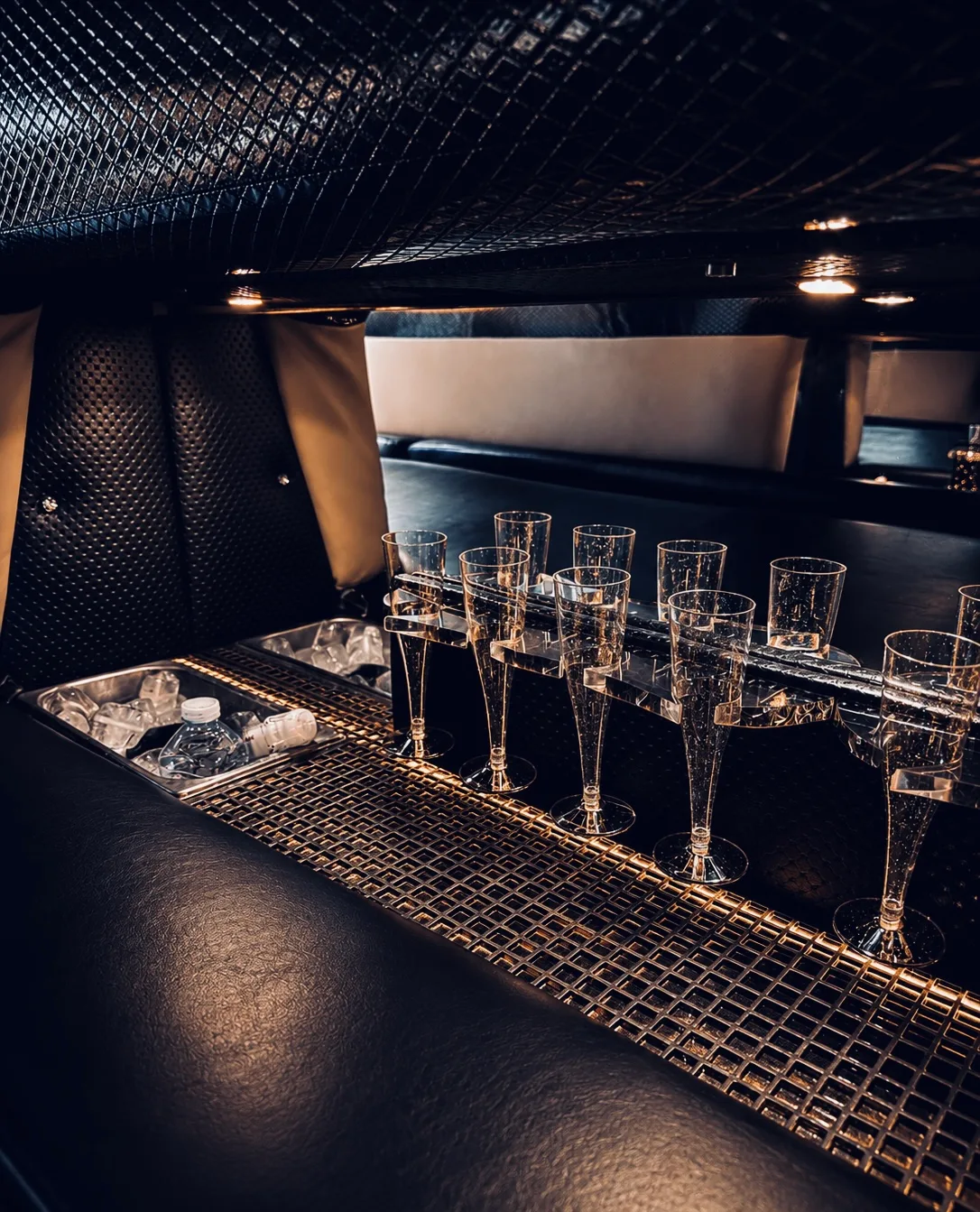 Copas de champán alineadas en el minibar iluminado del interior de la limusina
